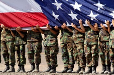 row of U.S. military holding an American flag