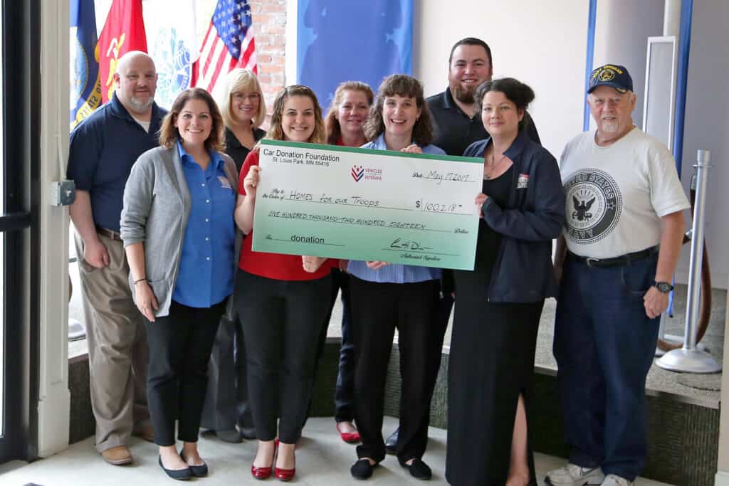 Veteran charity, Home for our Troops, staff holding a big check from Vehicles For Veterans car donation.