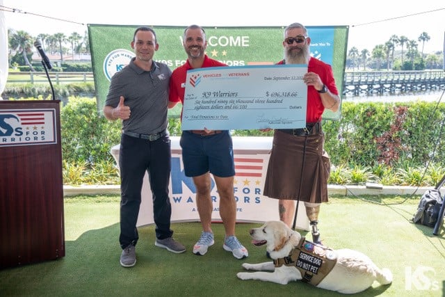 K9 warriors staff hold a big check from Vehicles For Veterans