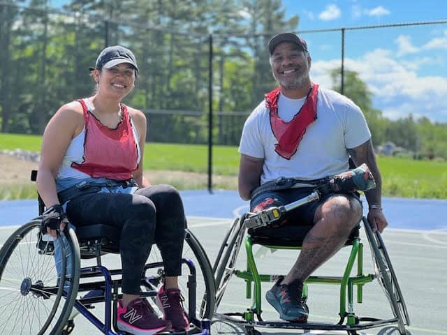 veteran couple in wheelchairs smiling and playing basketball