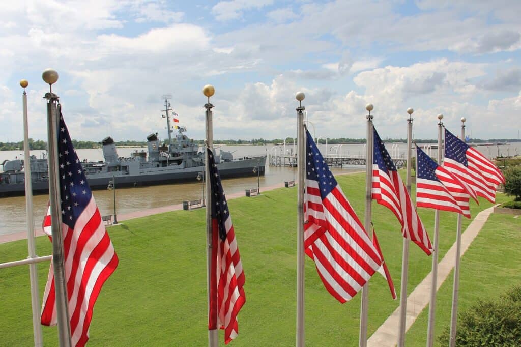 American flags near sea with Naval ship in background