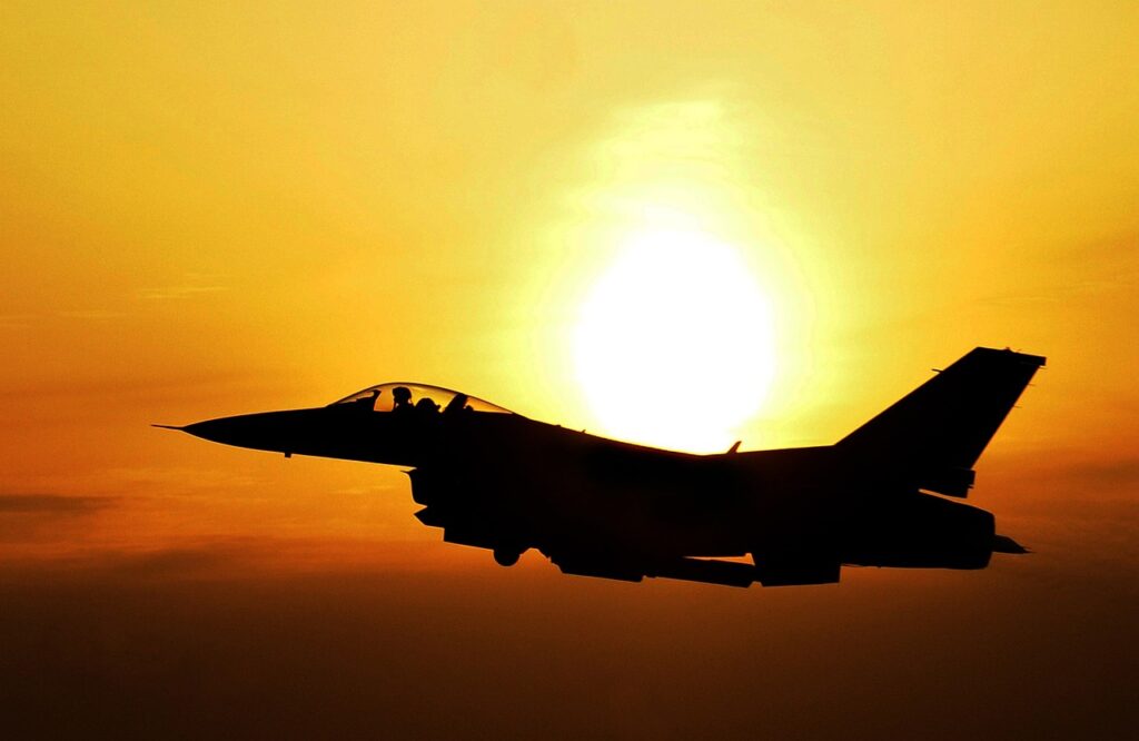 U.S. jet silhouette flying in front of sunset